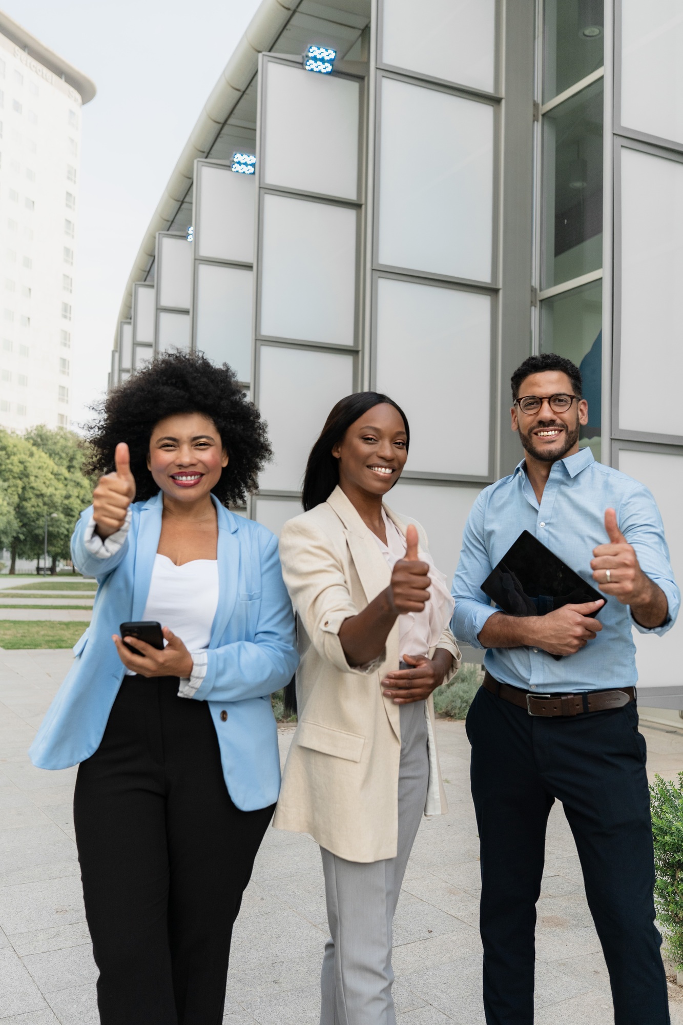 Group of multiracial diverse business team with thumbs up smiling at camera standing outside office